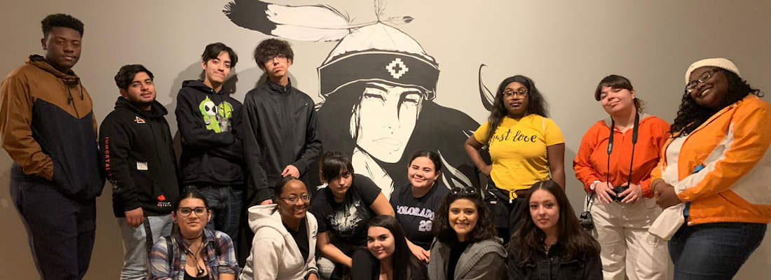 Students posing in a group in front of a mural